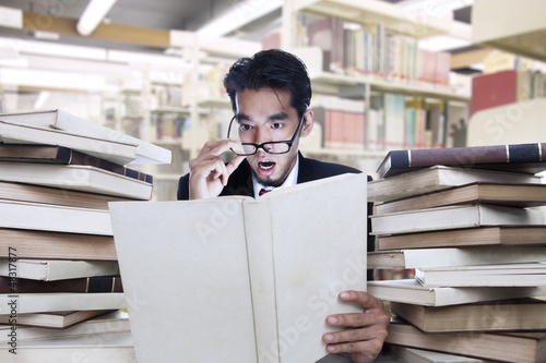 Photo: Businessman on shock looking at books Businessman on shock looking at books