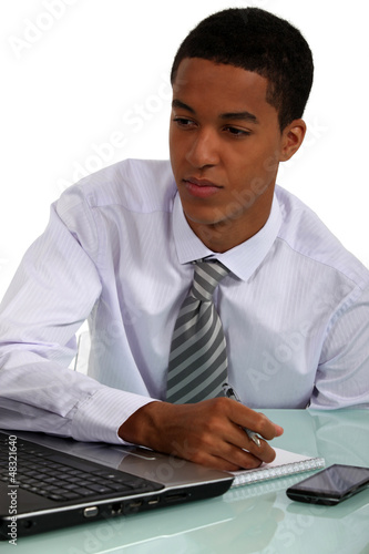 Photo: young Afro-American businessman working at his desk young Afro-American businessman working at his desk