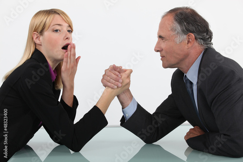 Photo: Blond woman arm wrestling her boss Blond woman arm wrestling her boss