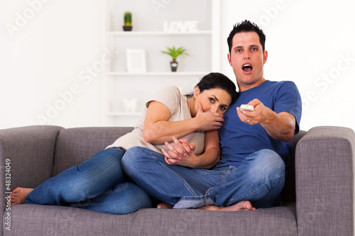 Photo: young couple watching scary horror movie at home young couple watching scary horror movie at home