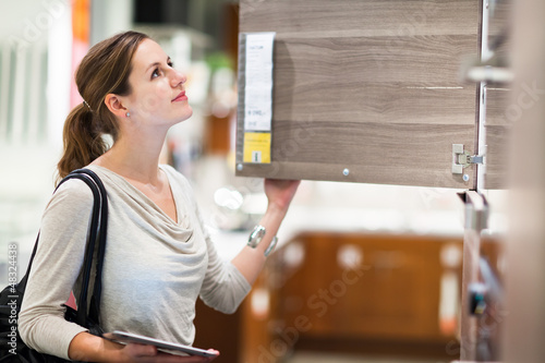 Photo: Young woman shopping for furniture in a furniture store Young woman shopping for furniture in a furniture store