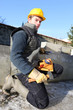 Foto: Mason kneeling by wall with lump hammer Mason kneeling by wall with lump hammer