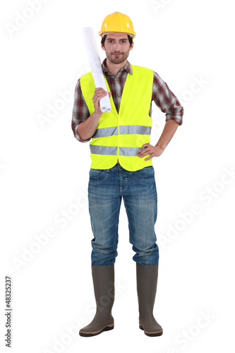 Photo: Engineer in a reflective vest with plans Engineer in a reflective vest with plans
