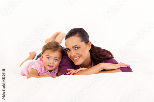 Photo: happy mother and baby girl lying on bed happy mother and baby girl lying on bed