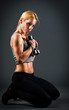 Fit woman holding weights over a dark background