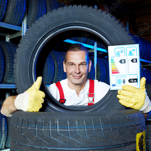 Photo: Motor mechanic shows thumb up for tire label in a garage Motor mechanic shows thumb up for tire label in a garage