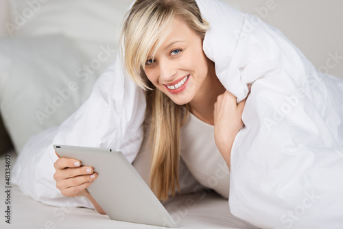 Photo: frau list mit e-reader im bett frau list mit e-reader im bett