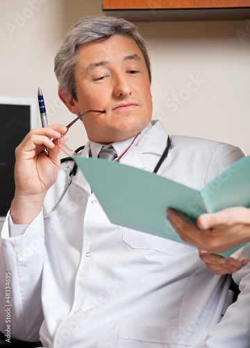 Photo: Doctor Reading Medical Report Doctor Reading Medical Report