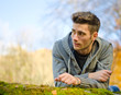 Photo: Attractive young man outdoors in nature lying on moss Attractive young man outdoors in nature lying on moss