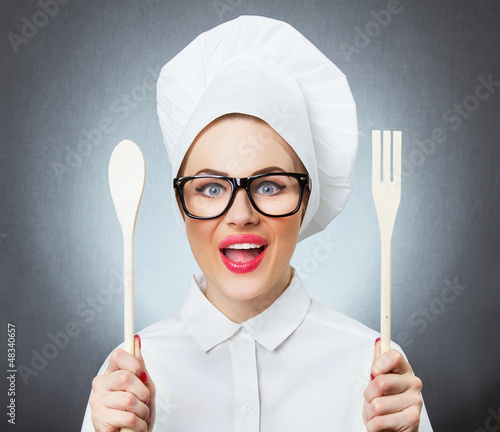 Photo: Portrait of laughing woman cook chef holding fork and spoon Portrait of laughing woman cook chef holding fork and spoon