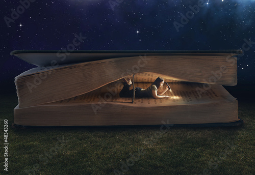 Photo: Woman reading inside a huge book Woman reading inside a huge book