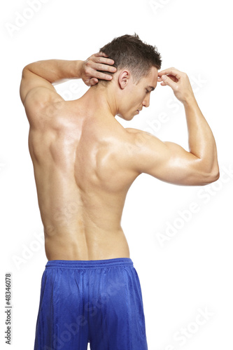 Photo: Muscular young man flexing arm muscles in sports outfit Muscular young man flexing arm muscles in sports outfit