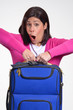 Joven mujer sujetando una maleta de viaje.
