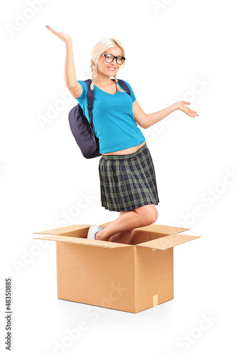 Photo: Excited female student with raised hands posing in a box Excited female student with raised hands posing in a box