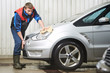 worker cleaning car with water and sponge