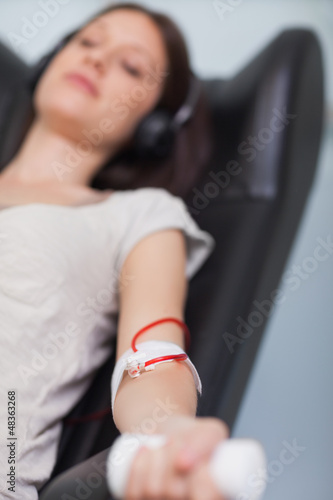 Photo: Patient listening to music while giving her blood in a hospital Patient listening to music while giving her blood in a hospital