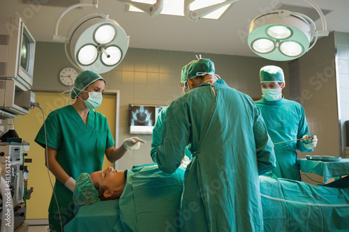 Photo: Group of surgeons working on a female patient Group of surgeons working on a female patient