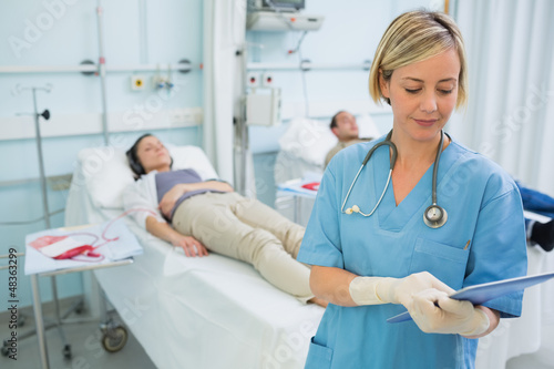 Photo: Nurse standing while looking at a clipboard Nurse standing while looking at a clipboard