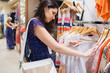 Photo: Woman with bag looking through clothes Woman with bag looking through clothes