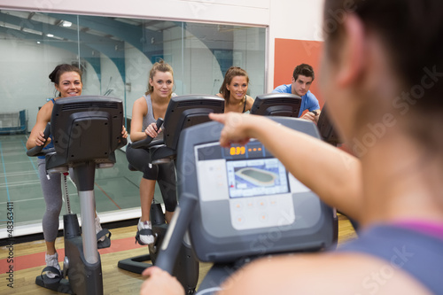 Photo: Instructor motivates happy people at spinning class Instructor motivates happy people at spinning class