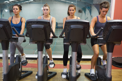 Photo: Four women working out at spinning class Four women working out at spinning class