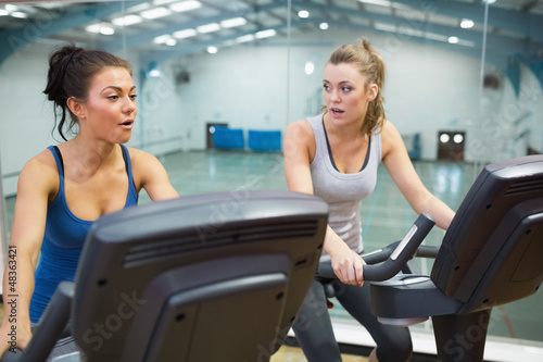 Photo: Two women working out on exercise bikes Two women working out on exercise bikes