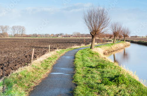Photo: Narrow bike path besides a meandering river. Narrow bike path besides a meandering river.