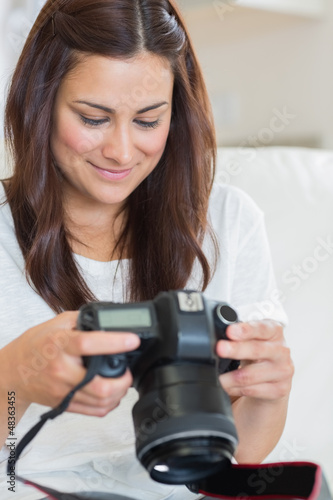 Photo: Brunette viewing photos while sitting on the sofa Brunette viewing photos while sitting on the sofa