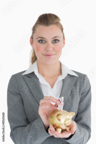 Photo: Woman putting money in the piggy bank Woman putting money in the piggy bank