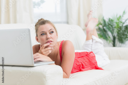 Photo: Woman looking thoughtful while using laptop Woman looking thoughtful while using laptop