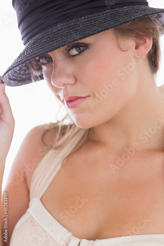 Photo: Woman in white holding black hat Woman in white holding black hat