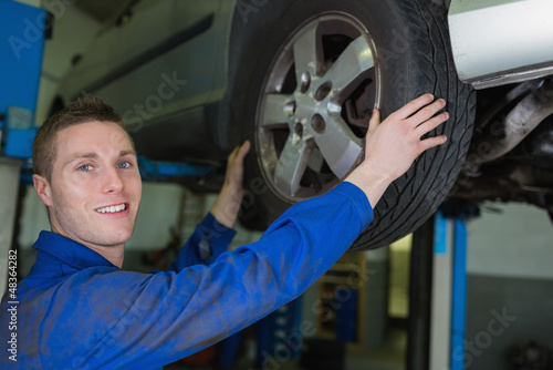 Photo: Male mechanic working on wheel of car Male mechanic working on wheel of car
