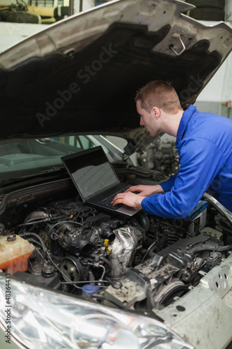 Photo: Mechanic using laptop on car engine Mechanic using laptop on car engine