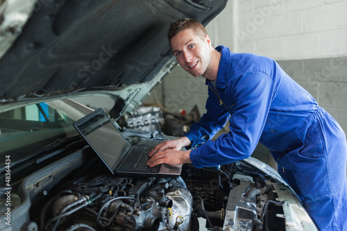 Photo: Male auto mechanic using laptop Male auto mechanic using laptop