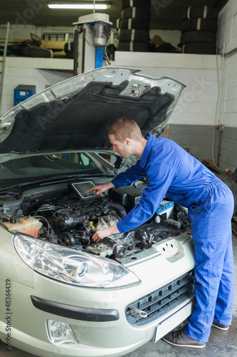 Photo: Male mechanic analyzing car engine Male mechanic analyzing car engine