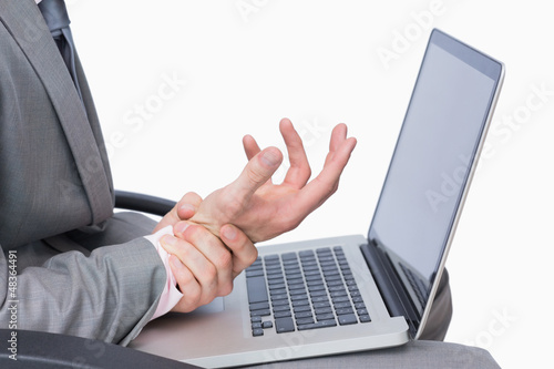 Photo: Business man with wrist pain while using laptop Business man with wrist pain while using laptop