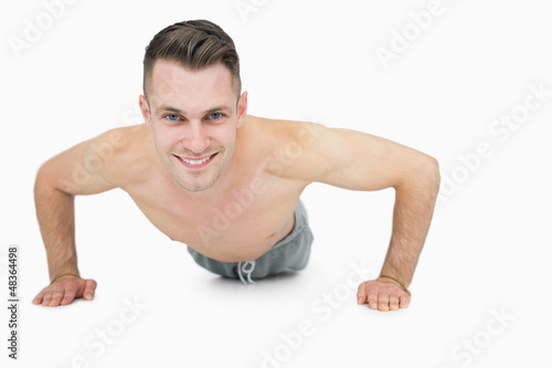 Photo: Portrait of happy shirtless man doing push ups Portrait of happy shirtless man doing push ups