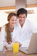 Couple using laptop over breakfast