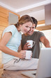 Couple using laptop while drinking coffee