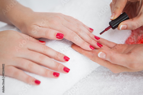 Photo: Woman applying nail varnish to finger nails Woman applying nail varnish to finger nails