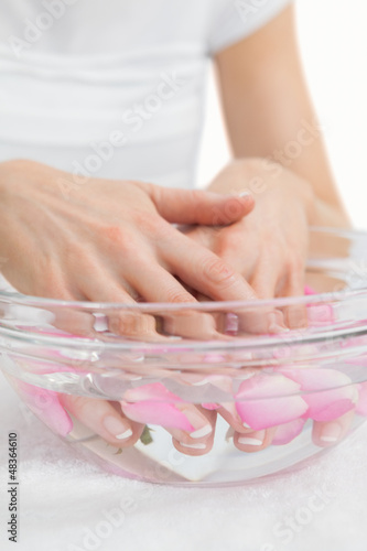 Photo: Woman's hands in bowl with petals at hands spa Woman's hands in bowl with petals at hands spa