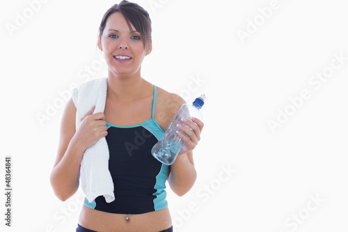 Photo: Portrait of woman in sportswear holding towel around neck and wa Portrait of woman in sportswear holding towel around neck and wa