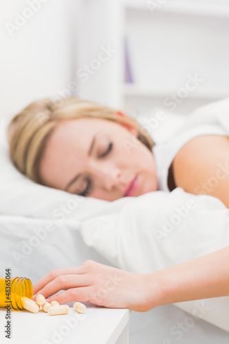 Photo: Asleep woman with focus on spilt bottle of pills at home Asleep woman with focus on spilt bottle of pills at home