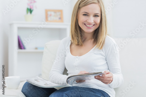 Photo: Portrait of young woman with magazine at home Portrait of young woman with magazine at home