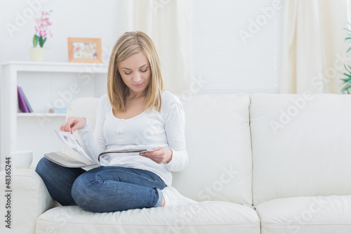 Photo: Casual young woman reading magazine at home Casual young woman reading magazine at home