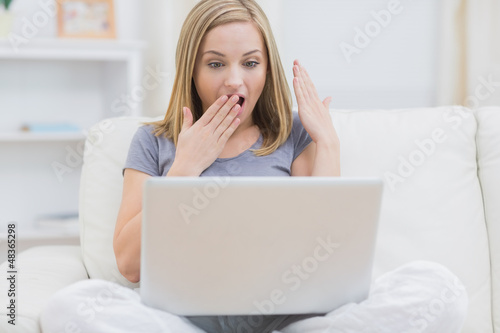 Photo: Surprised casual woman using laptop at home Surprised casual woman using laptop at home