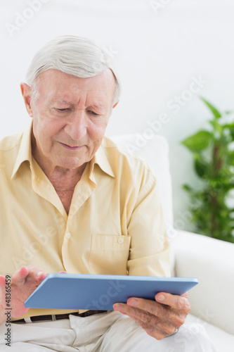 Photo: Elderly focused man using a digital tablet Elderly focused man using a digital tablet
