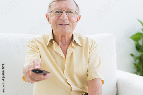 Photo: Smiling elderly man using the remote Smiling elderly man using the remote
