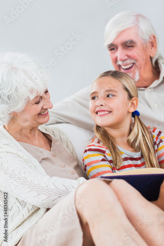 Photo: Happy grandparents reading with granddaughter Happy grandparents reading with granddaughter
