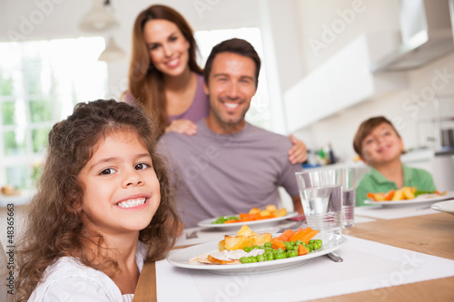 Photo: Family smiling at the camera at dinner table Family smiling at the camera at dinner table